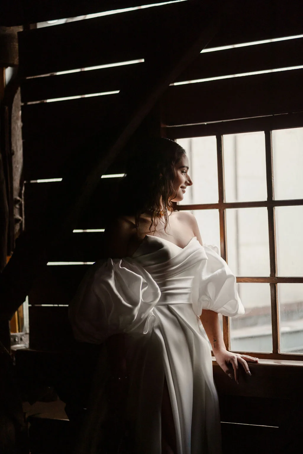 La mariée devant une grande fenêtre, dans la pénombre