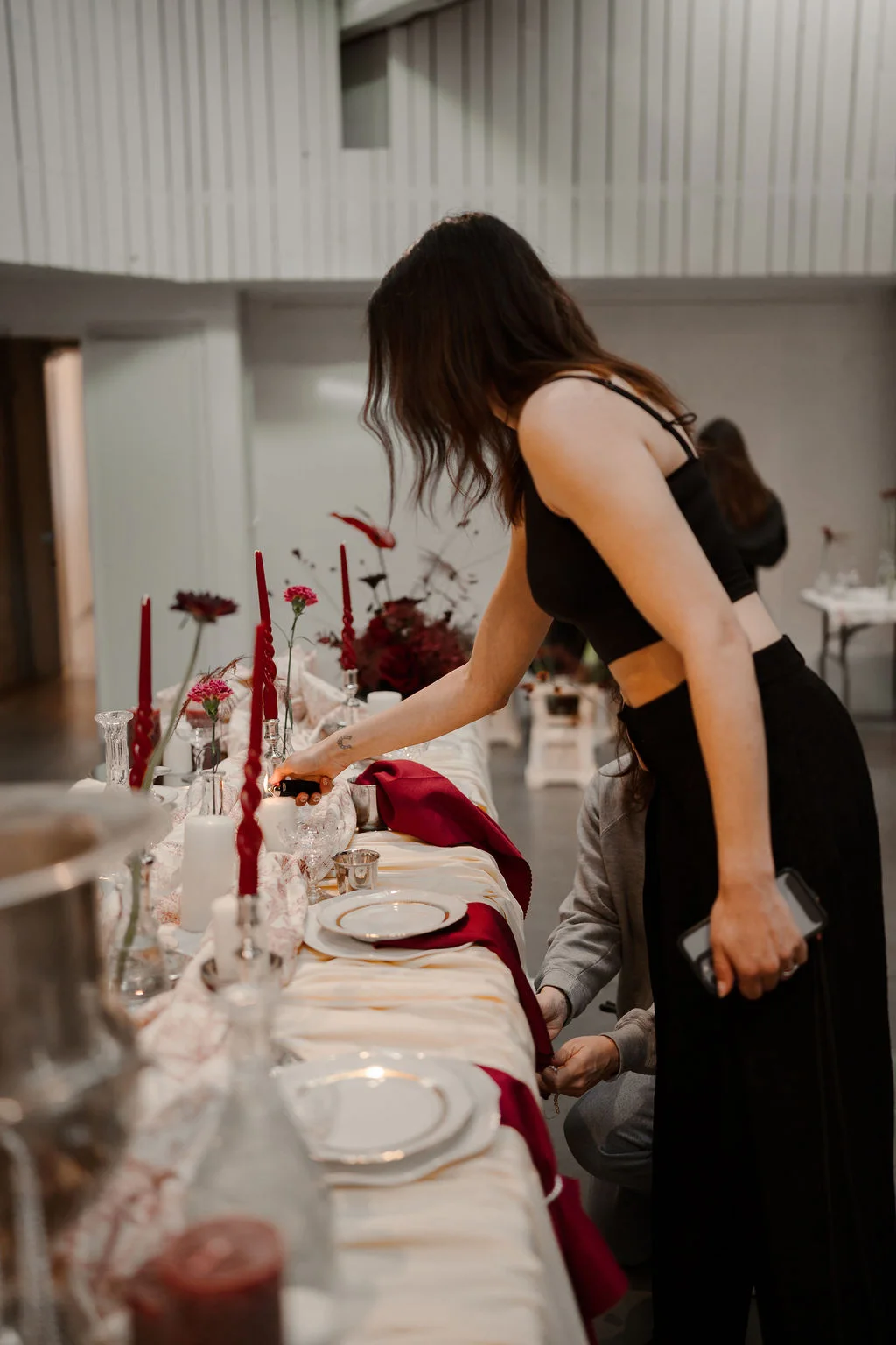 Sara ajuste les bougies et les fleurs d'une table dressée